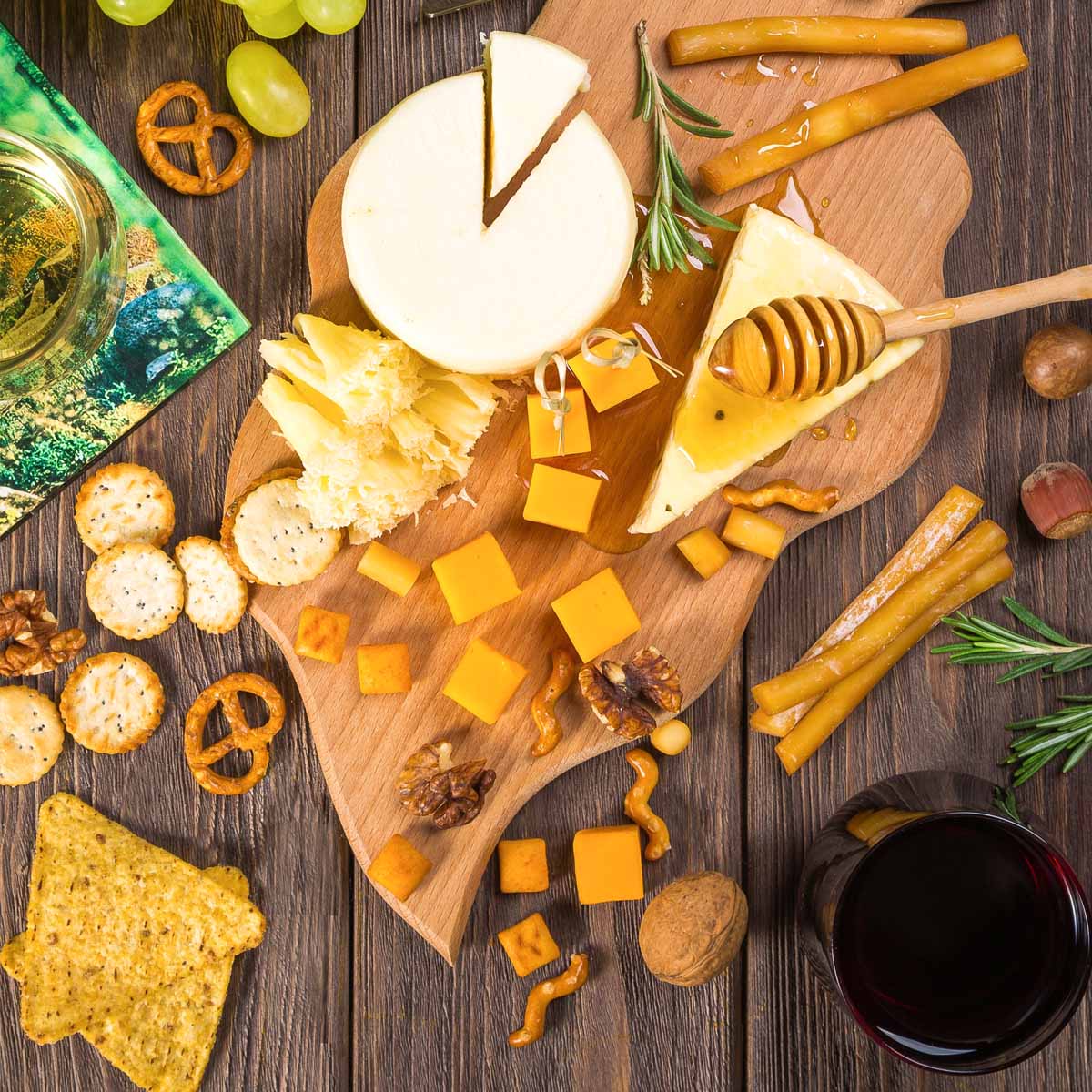 Best Cheeses for a Charcuterie Board A wooden board featuring various cheeses, crackers, nuts, and honey, perfect for a charcuterie board.