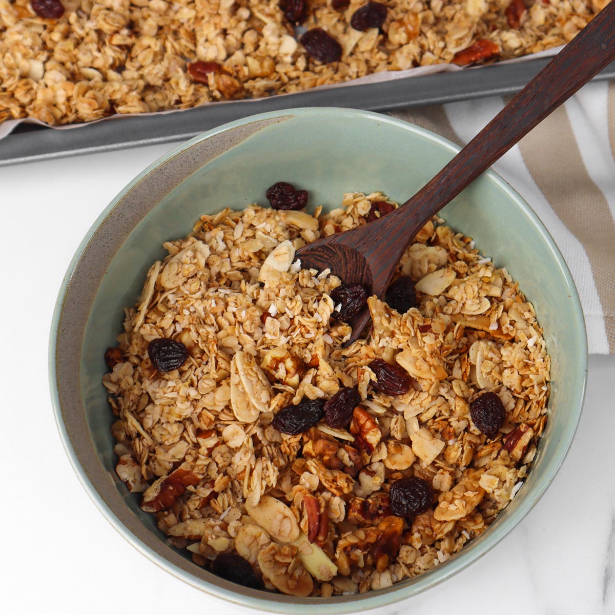 Granola Un bol de granola aux noix et aux raisins secs, accompagné d'une cuillère en bois.