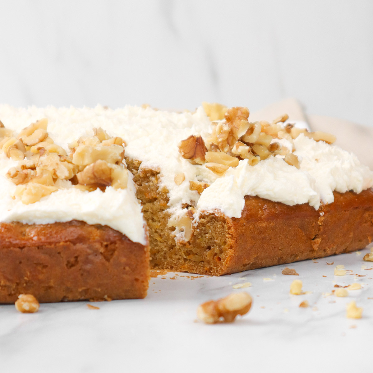 Veganistische worteltaart Een stuk veganistische worteltaart met room en gehakte walnoten.