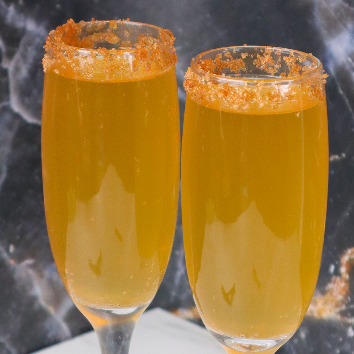 Mimosas de cidra de maçã Duas taças de mimosa de cidra de maçã com a borda açucarada.