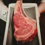 Tampilan dekat potongan iga panggang yang dipajang di atas piring, memperlihatkan tekstur marmernya.