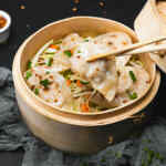 Kukusan bambu berisi pangsit dan sayuran, siap disajikan sebagai dim sum.