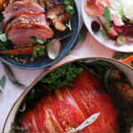 Piring berisi irisan ham, sayuran panggang, dan salad segar, menonjolkan berbagai hidangan daging babi.