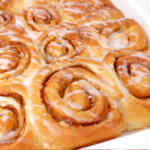 Roti gulung kayu manis yang baru dipanggang, dilumuri dengan lapisan gula dalam loyang.