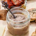 Olive tapenade in a small glass jar with a small spoon