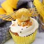 Kue mangkuk burung golden snitch yang diberi hiasan sayap emas dan taburan warna-warni.