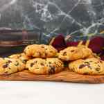 Papan kayu dengan beberapa kue batu bergambar kismis, diletakkan pada latar belakang marmer gelap.