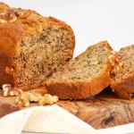 Roti pisang dan kenari diiris pada papan kayu dengan taburan kenari di sekelilingnya.