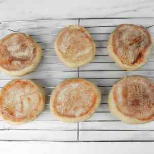 Des muffins anglais fraîchement sortis du four refroidissent sur une grille.