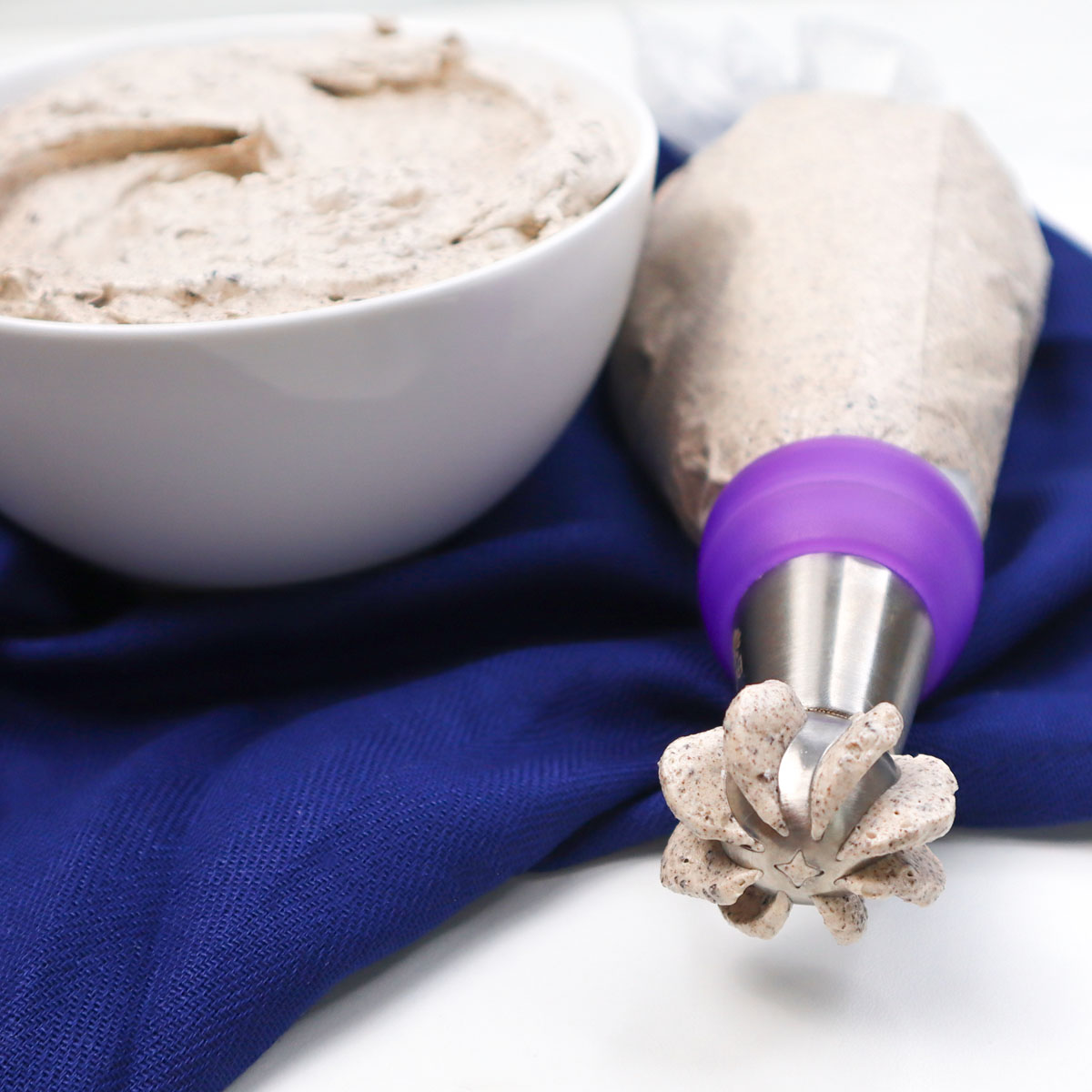 Semangkuk krim mentega Oreo di samping kantung semprot dengan ujung dekoratif.
