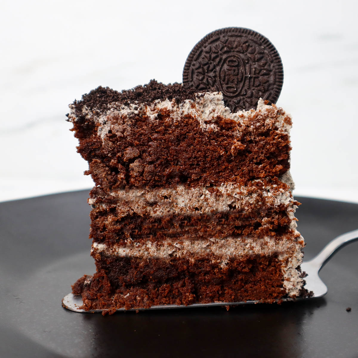 Sepotong kue coklat berlapis krim dan diberi kue di atasnya.