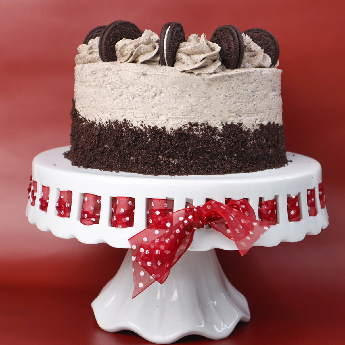 Kue Oreo berlapis dengan lapisan gula dan hiasan kue di atas tatakan kue putih.