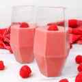 Two glasses of raspberry banana smoothie topped with fresh raspberries.