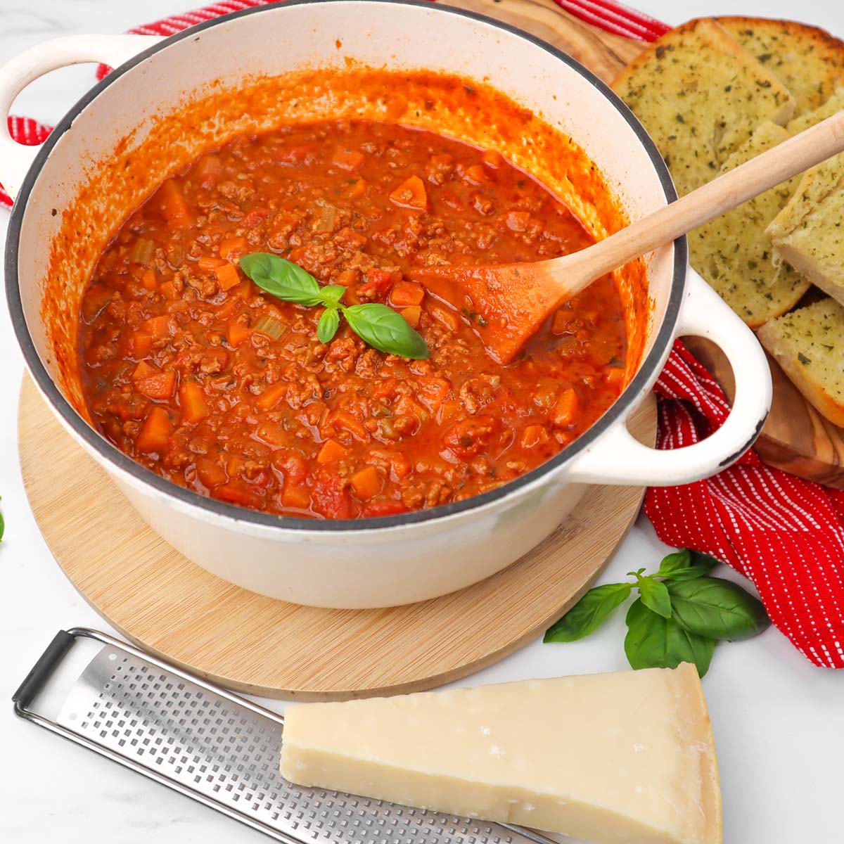 A pot of traditional spaghetti Bolognese with fresh basil and garlic bread on the side.