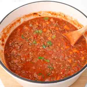A pot of rich spaghetti Bolognese sauce with ground meat, vegetables, and herbs.