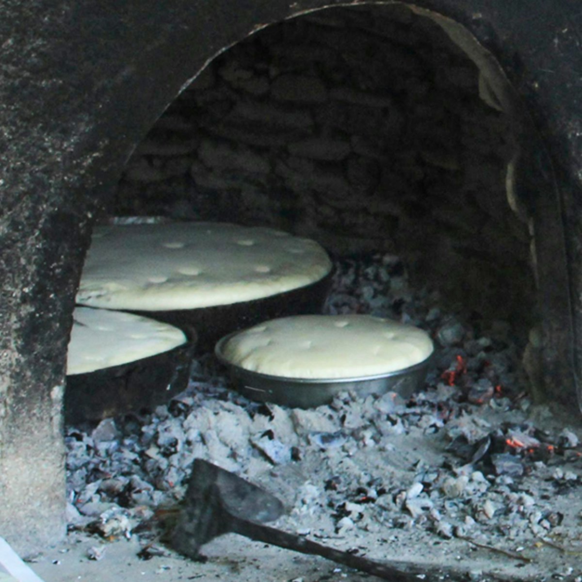 Pão grego tradicional sendo assado em forno ao ar livre