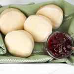 Muffin Inggris yang baru dibuat dengan air fryer, disajikan dengan selai di atas kain hijau.