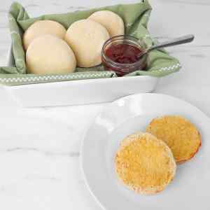 Muffins anglais fraîchement cuits à l'air chaud, servis avec de la confiture dans un panier.