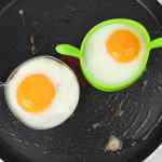 Dua butir telur dimasak dalam cetakan melingkar di atas wajan penggorengan.