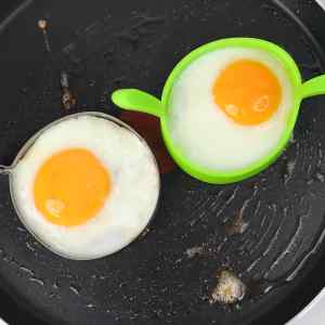 Deux œufs cuits dans des moules ronds à la poêle.