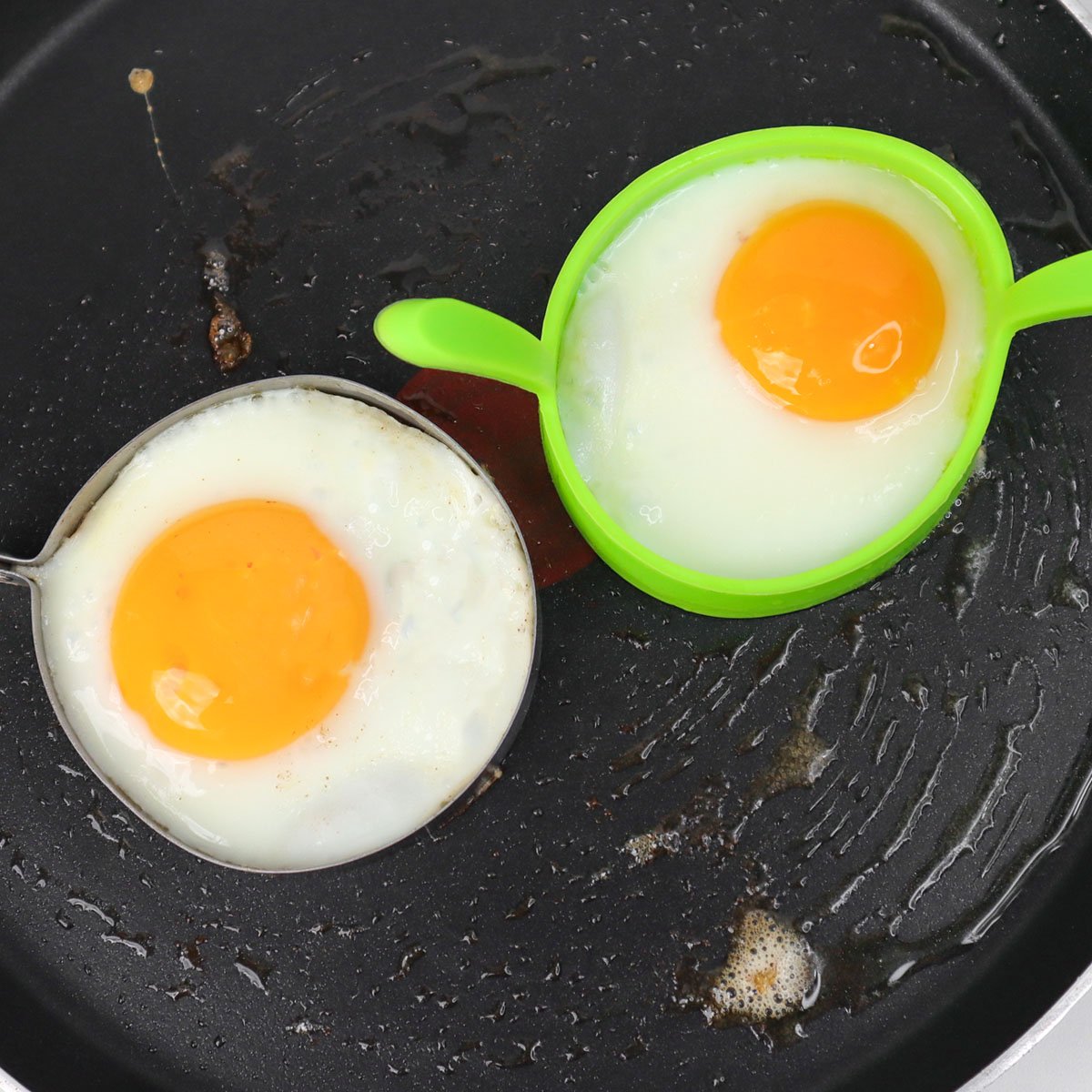 Deux œufs cuits dans des moules ronds à la poêle.