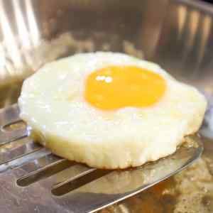 Un œuf parfaitement cuit, disposé en cercle, posé sur une spatule.