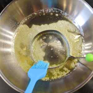 Un bol contenant du beurre fondu et un cercle métallique rond pour cuire les œufs.