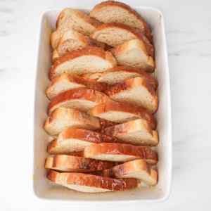 Sliced bread arranged in a baking dish, ready for baked French toast.