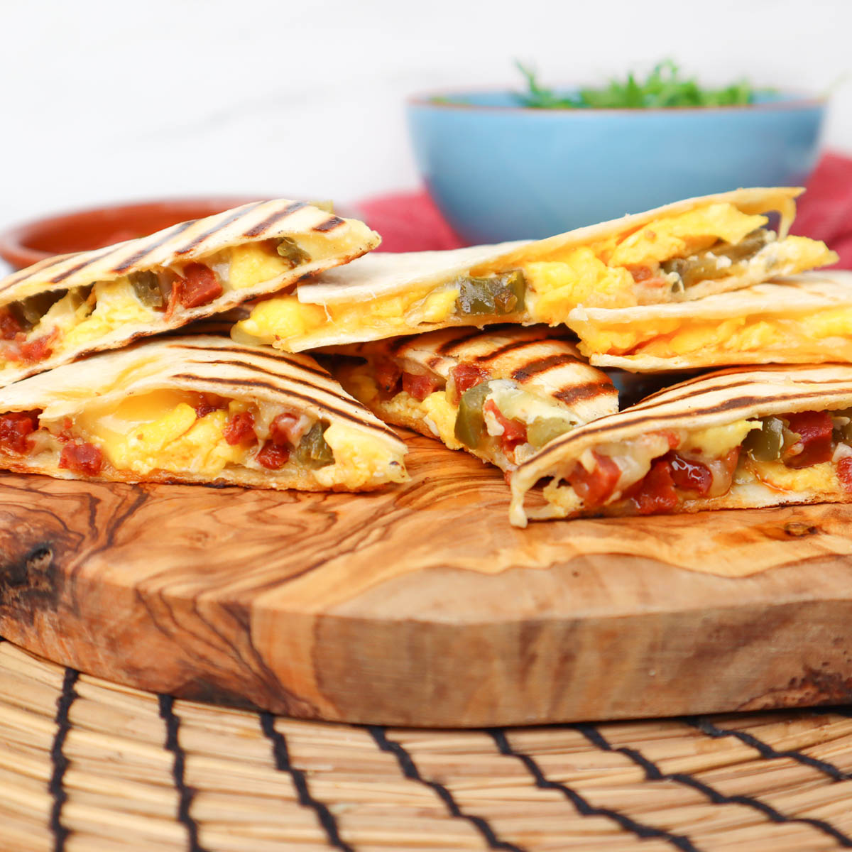 Quesadillas du petit-déjeuner Quesadillas grillées pour le petit-déjeuner, garnies d'œufs, de tomates et de poivrons, servies sur une planche en bois.