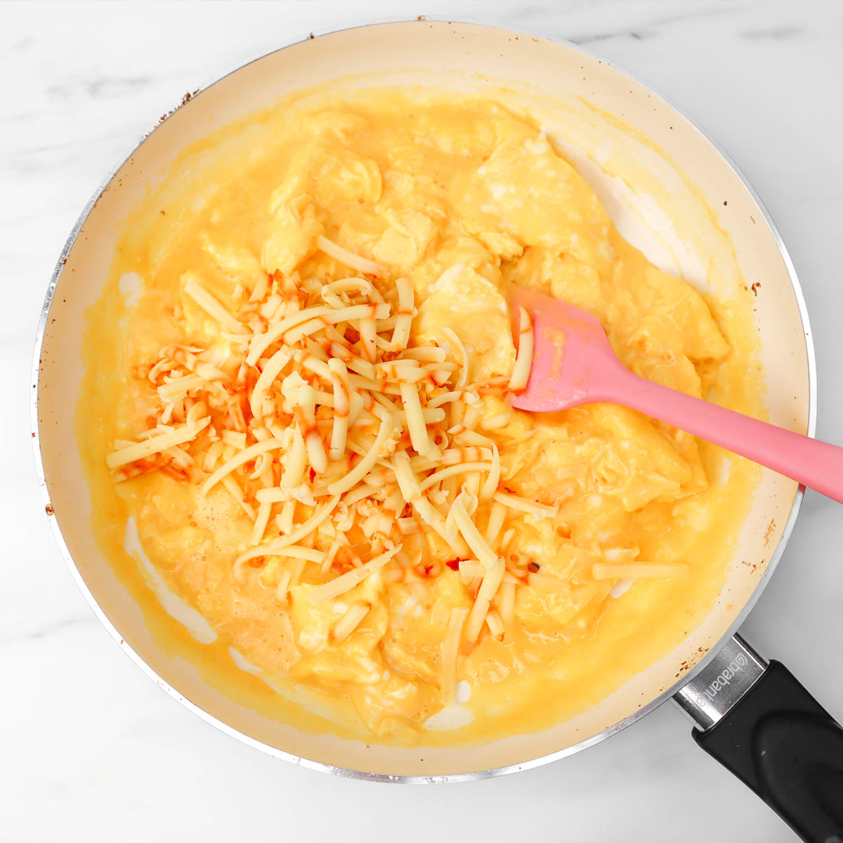 Tacos du petit-déjeuner Des œufs brouillés avec du fromage fondu dans une poêle, prêts pour des tacos au petit-déjeuner.