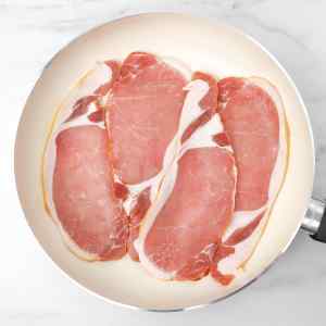 Tranches de bacon disposées dans une poêle, prêtes à cuire.