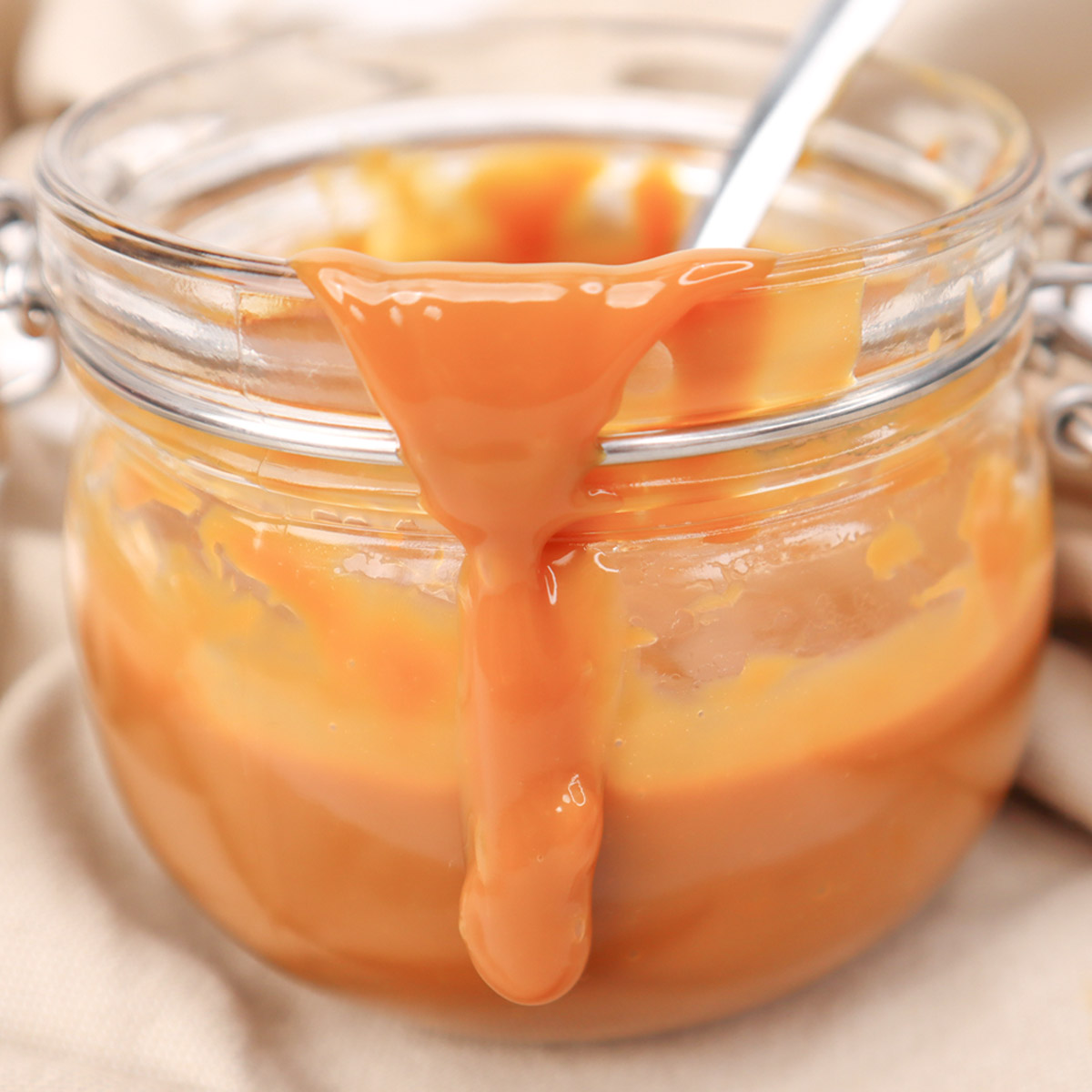 Caramel Sauce A jar of smooth caramel sauce with some dripping down the side.