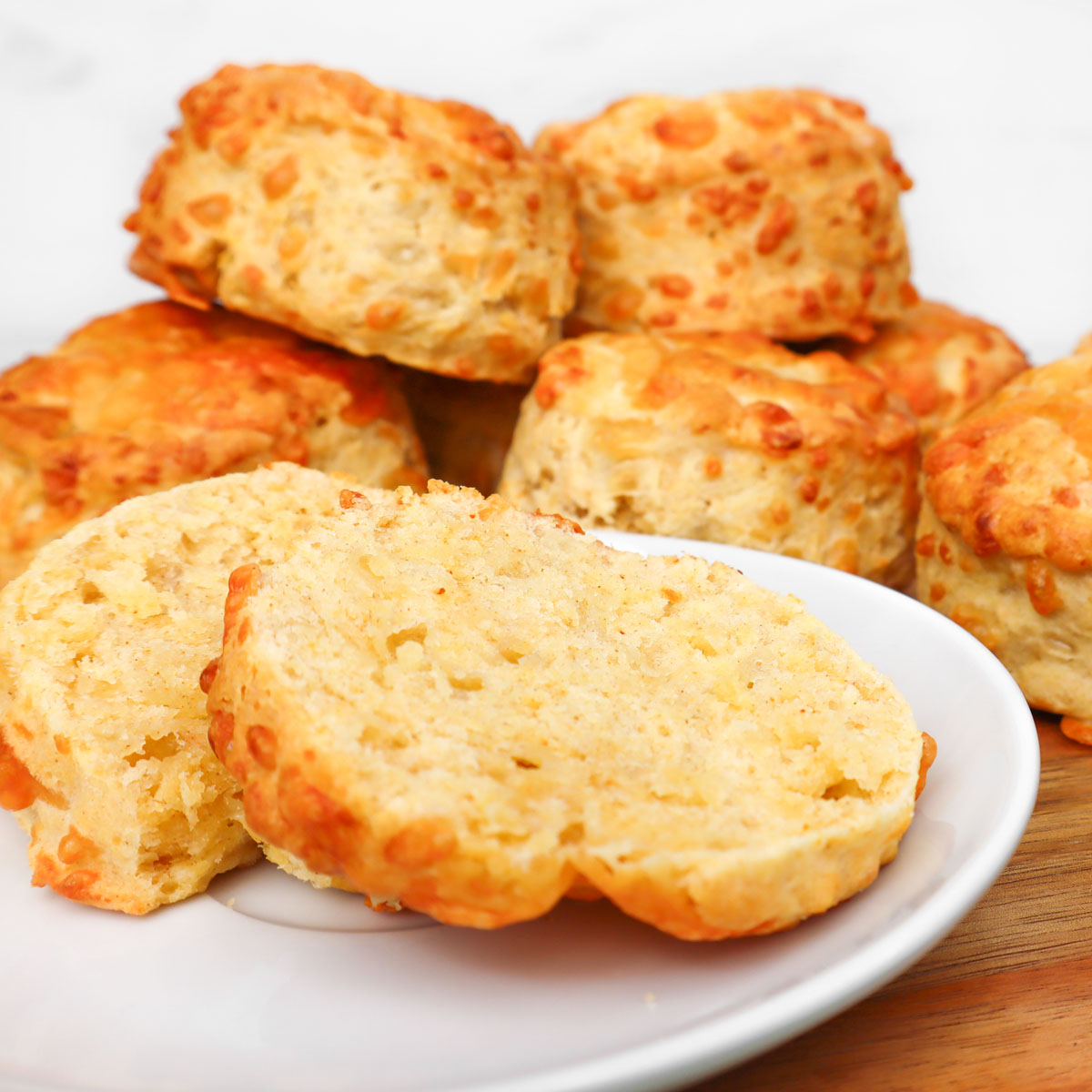 Scones de queijo Scones de queijo recém-assados em um prato, com um deles cortado ao meio para mostrar o interior fofo.