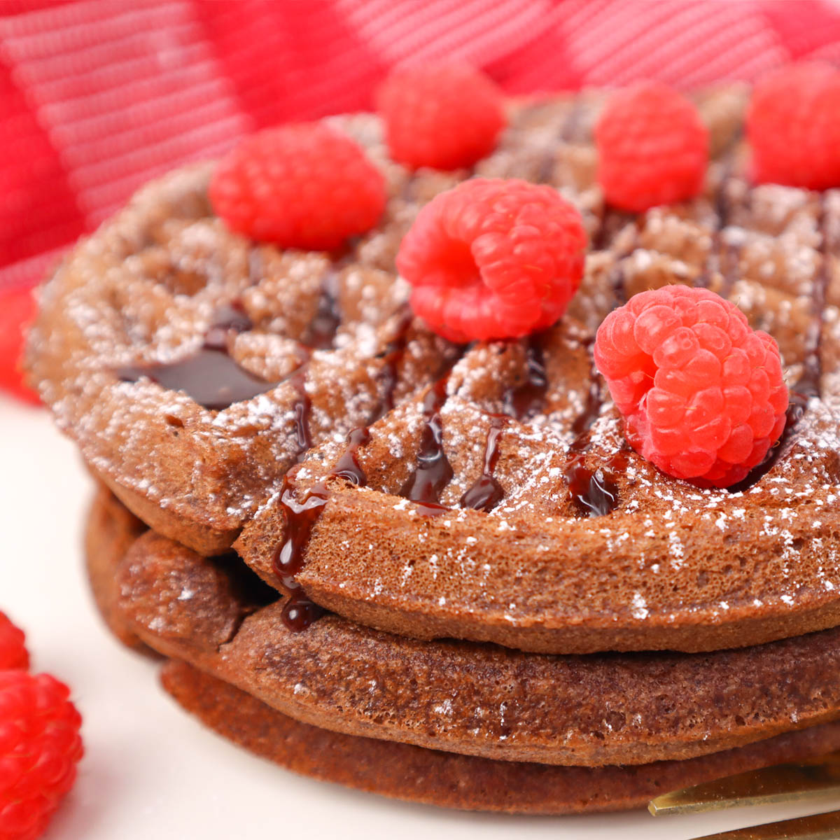 Gaufres au chocolat Pile de gaufres au chocolat garnies de framboises et nappées de sauce au chocolat.