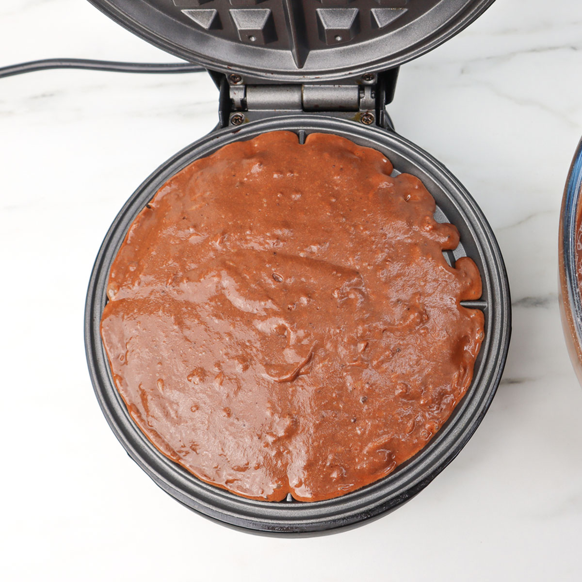 Gaufres au chocolat La pâte est versée dans un gaufrier, prête à cuire des gaufres au chocolat.