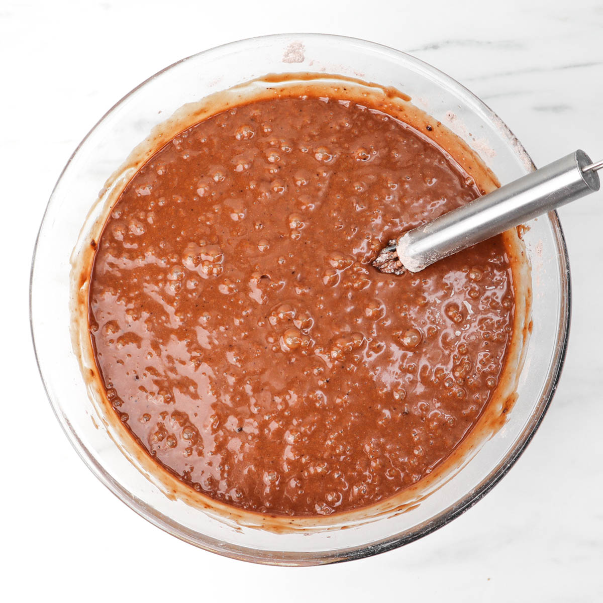 Gaufres au chocolat Un bol de pâte à gaufres au chocolat avec un fouet posé à l'intérieur.