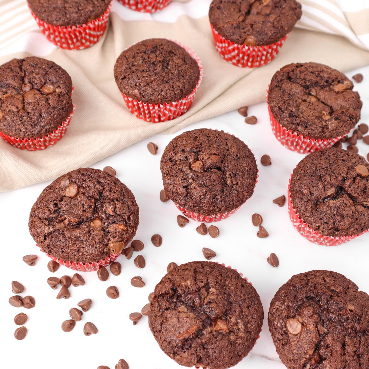 Muffins au chocolat et à la courgette Muffins au chocolat et à la courgette fraîchement sortis du four, dans des caissettes rouges, parsemés de pépites de chocolat.