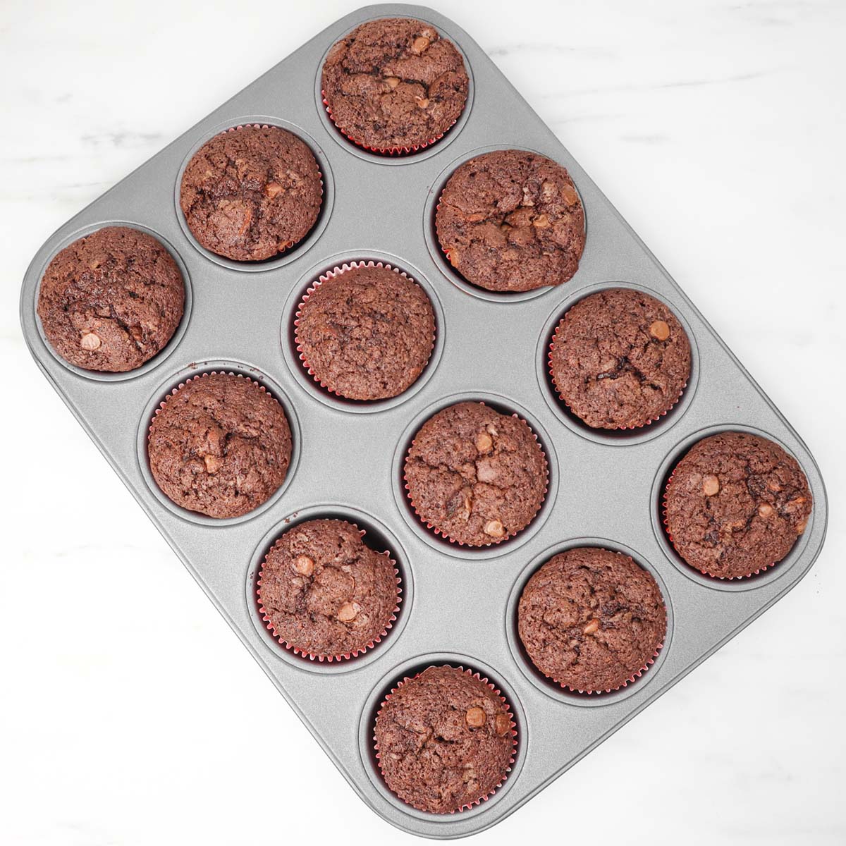 Muffins au chocolat et à la courgette Un plateau de muffins au chocolat et à la courgette fraîchement sortis du four, dans des caissettes en papier.