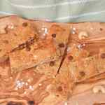 Homemade granola bars with chocolate chips on a wooden platter.