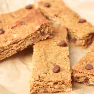 Gros plan sur des barres de granola maison aux pépites de chocolat, présentées sur du papier sulfurisé.