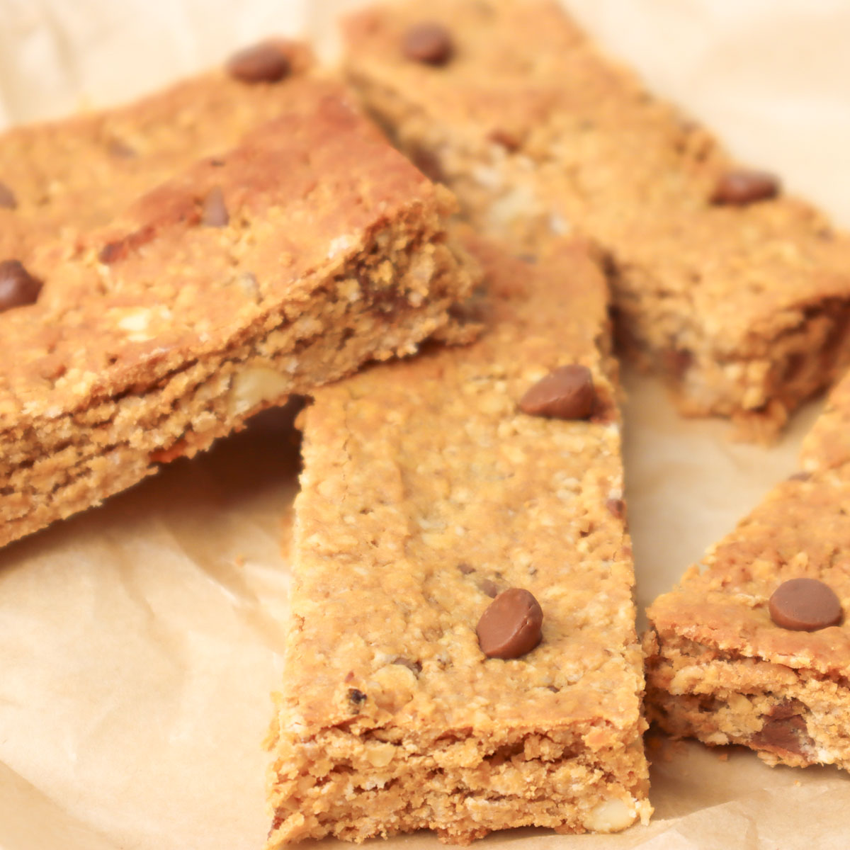 Barres de granola Gros plan sur des barres de granola maison aux pépites de chocolat, présentées sur du papier sulfurisé.