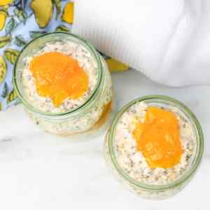 Dois potes de aveia adormecida com creme de limão, cobertos com um creme de limão amarelo brilhante.