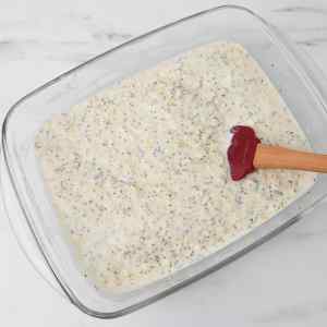 Um recipiente de vidro contendo aveia adormecida com creme de limão e sementes de chia, e uma espátula.