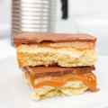 A close-up of two layers of Millionaires Shortbread, featuring a caramel filling and chocolate topping.
