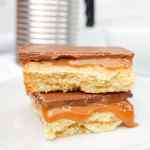 Un primer plano de dos capas de galletas Millionaires Shortbread, con relleno de caramelo y cobertura de chocolate.