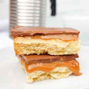 Um close-up de duas camadas de Millionaires Shortbread, com recheio de caramelo e cobertura de chocolate.