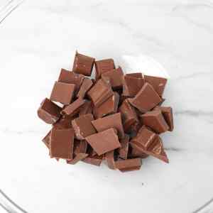 Uma tigela cheia de pedaços de chocolate picados, prontos para derreter.