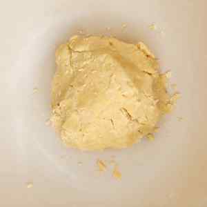 Uma bola de massa de biscoito amanteigado em uma tigela, pronta para assar.