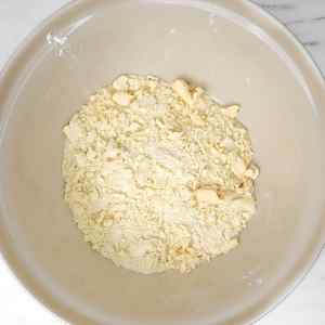 Uma tigela cheia de uma mistura esfarelada, para servir de base para uma sobremesa.