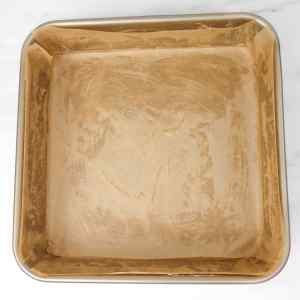 Uma assadeira forrada com papel manteiga, apresentando sinais de uso anterior.